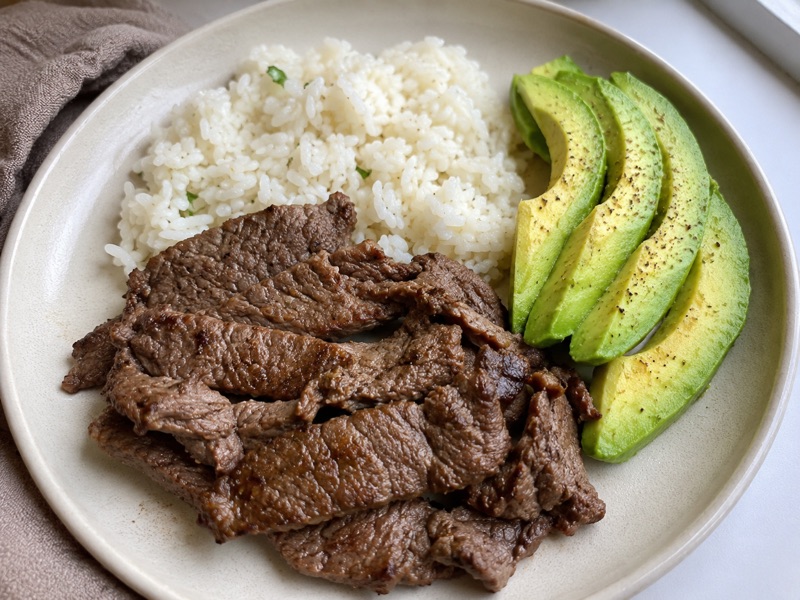 Plato de res asada en tiras con arroz blanco y aguacate en rebanadas